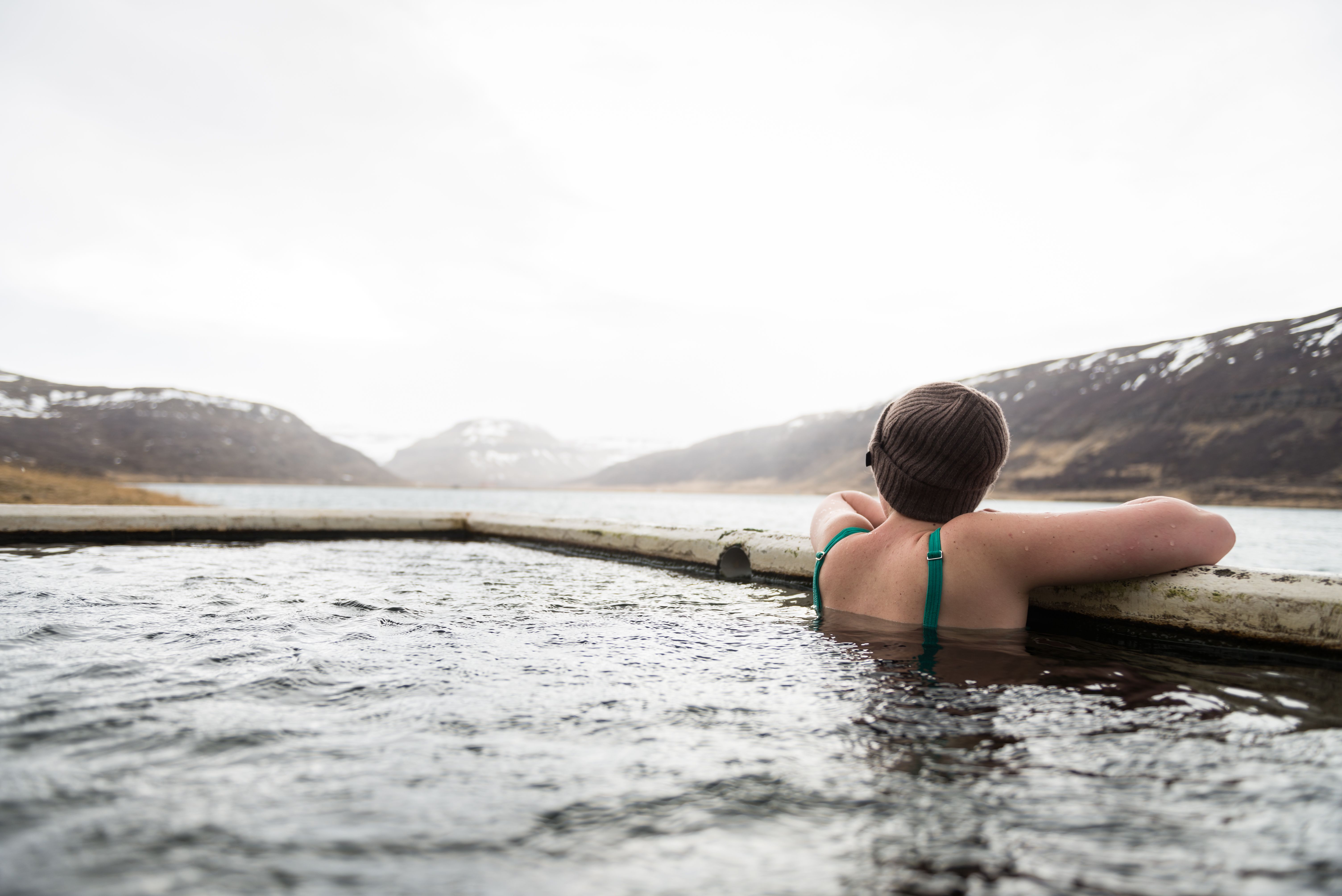Guest relaxing in a hot spring pool surrounded by snowy mountain scenery.
