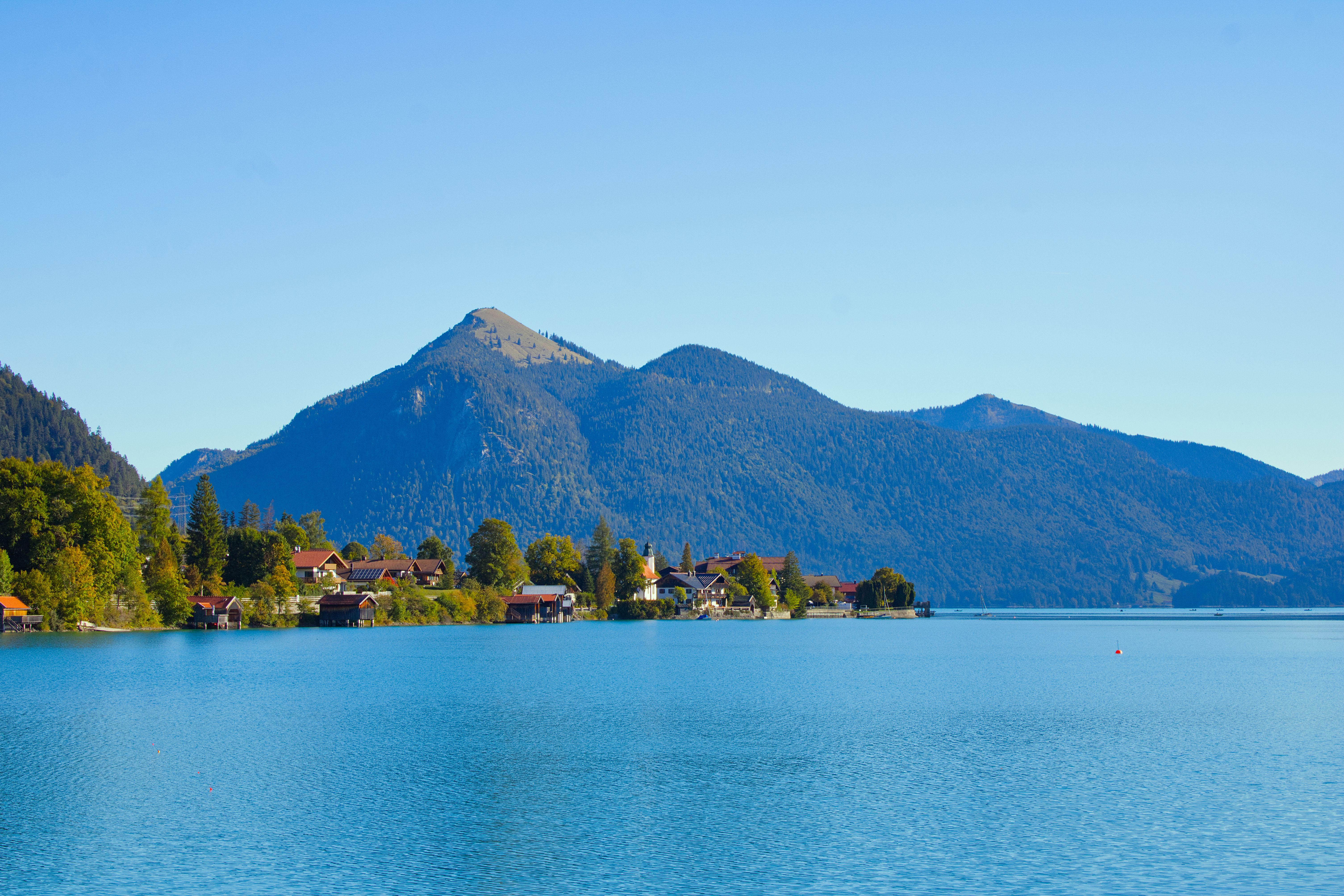 Bavarian lake, mountain and village landscape beneath clear skies.